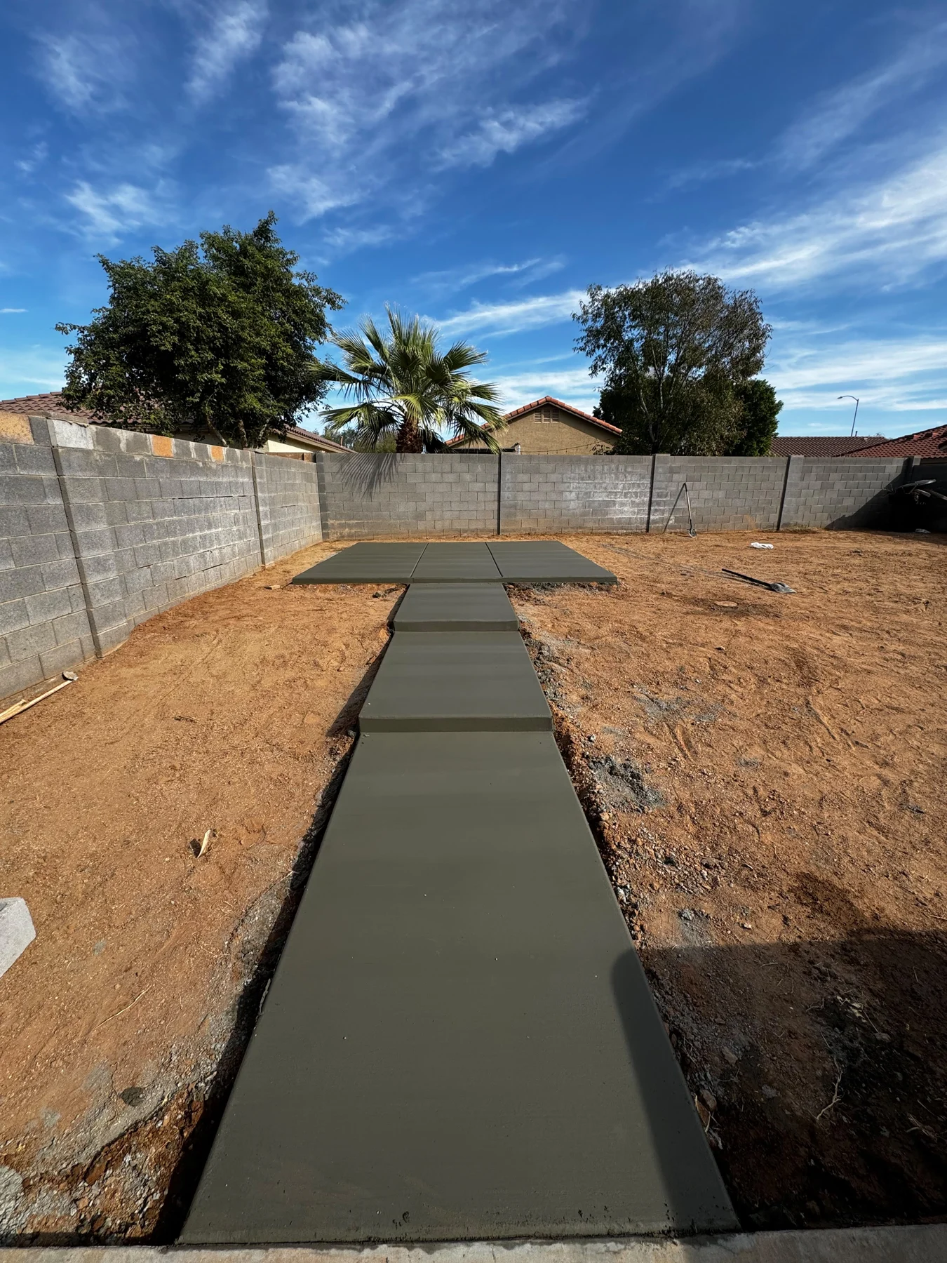 New concrete garden walkway leading through a desert backyard